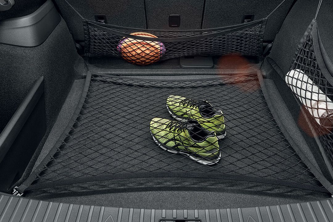 Škoda Kodiaq Netzsystem für den Kofferraum. Sportschuhe, ein Football und eine Trinkflasche befinden sich in den Netzen.