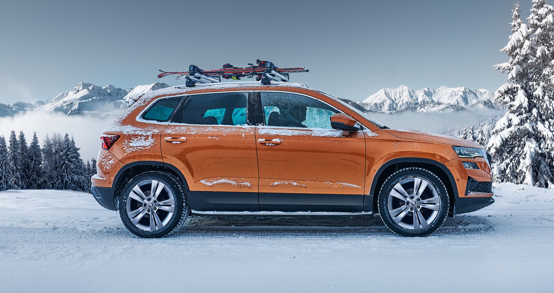 Ein Škoda Karoq mit Skiträger parkt in winterlicher Landschaft