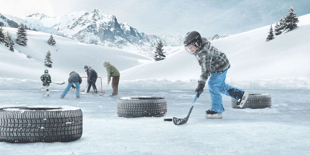 Škoda Winterreifen liegen auf einer Eisfläche. Kinder spielen Eishockey.