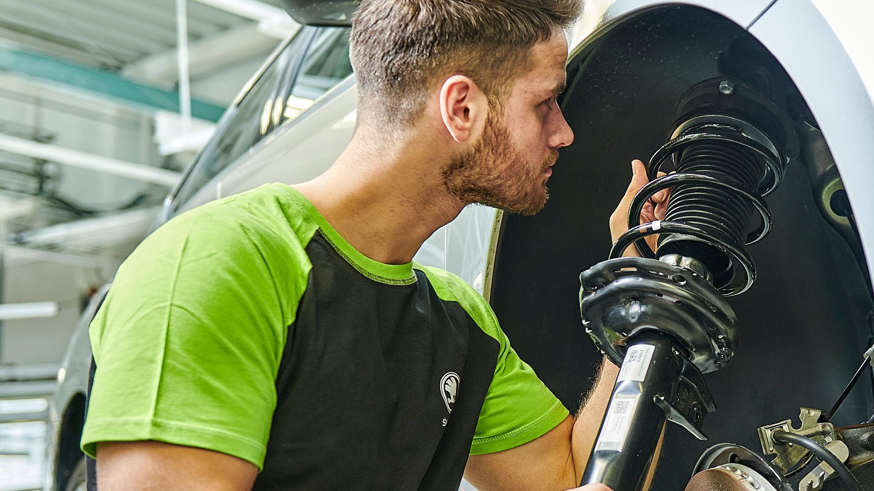 Ein Škoda Mechaniker wechselt die Stoßdämpfer bei einem Škoda