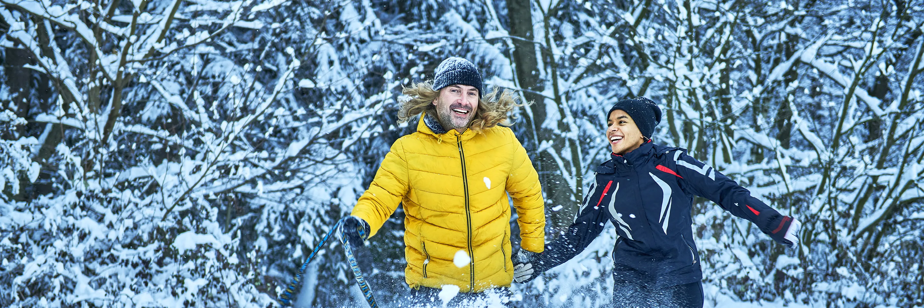 Ein Mann und eine Frau spielen  mit ihrem Hund im Schnee