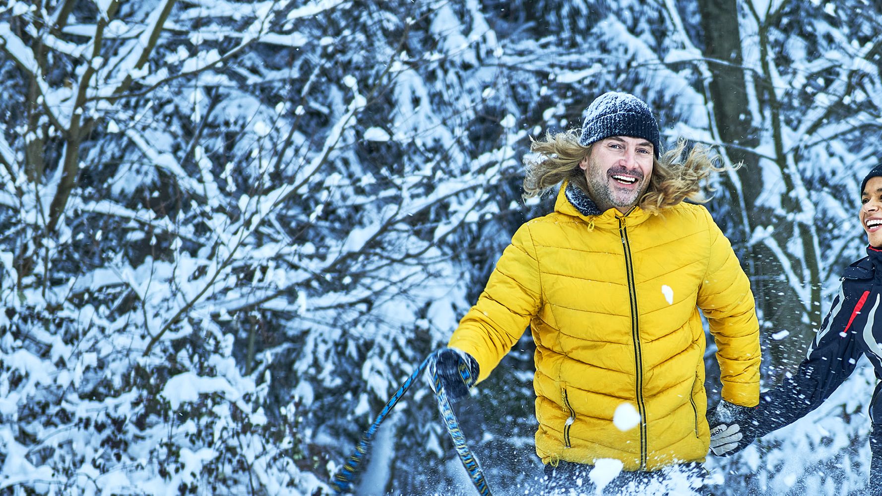 Ein Mann und eine Frau spielen  mit ihrem Hund im Schnee