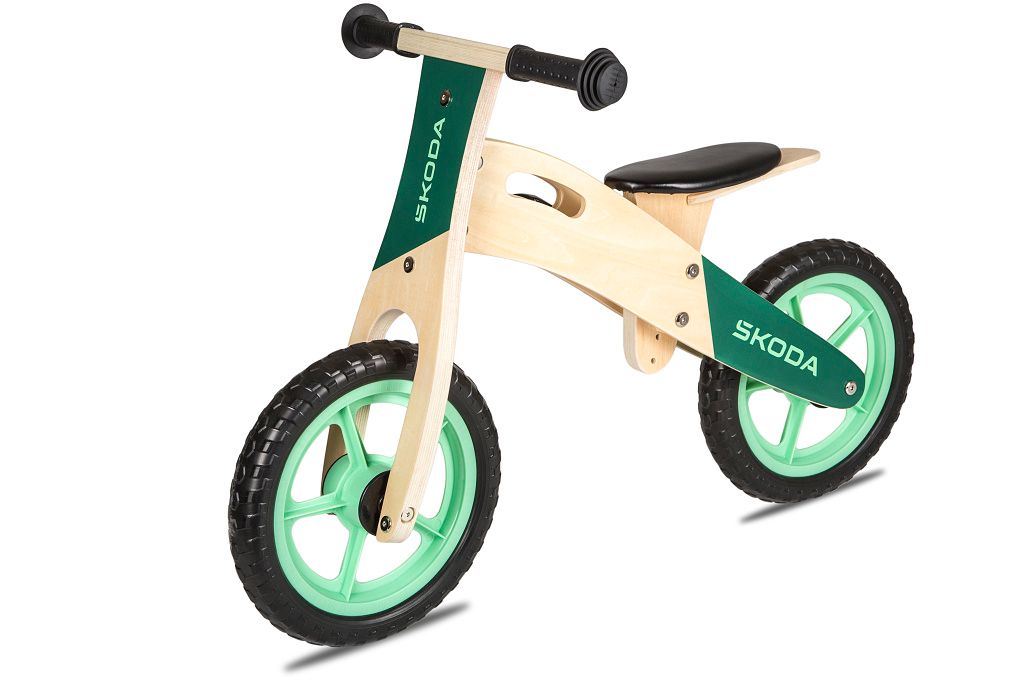 Ein Škoda Kinder-Laufrad aus Holz mit Škoda Logo und grünen Fahrradfelgen