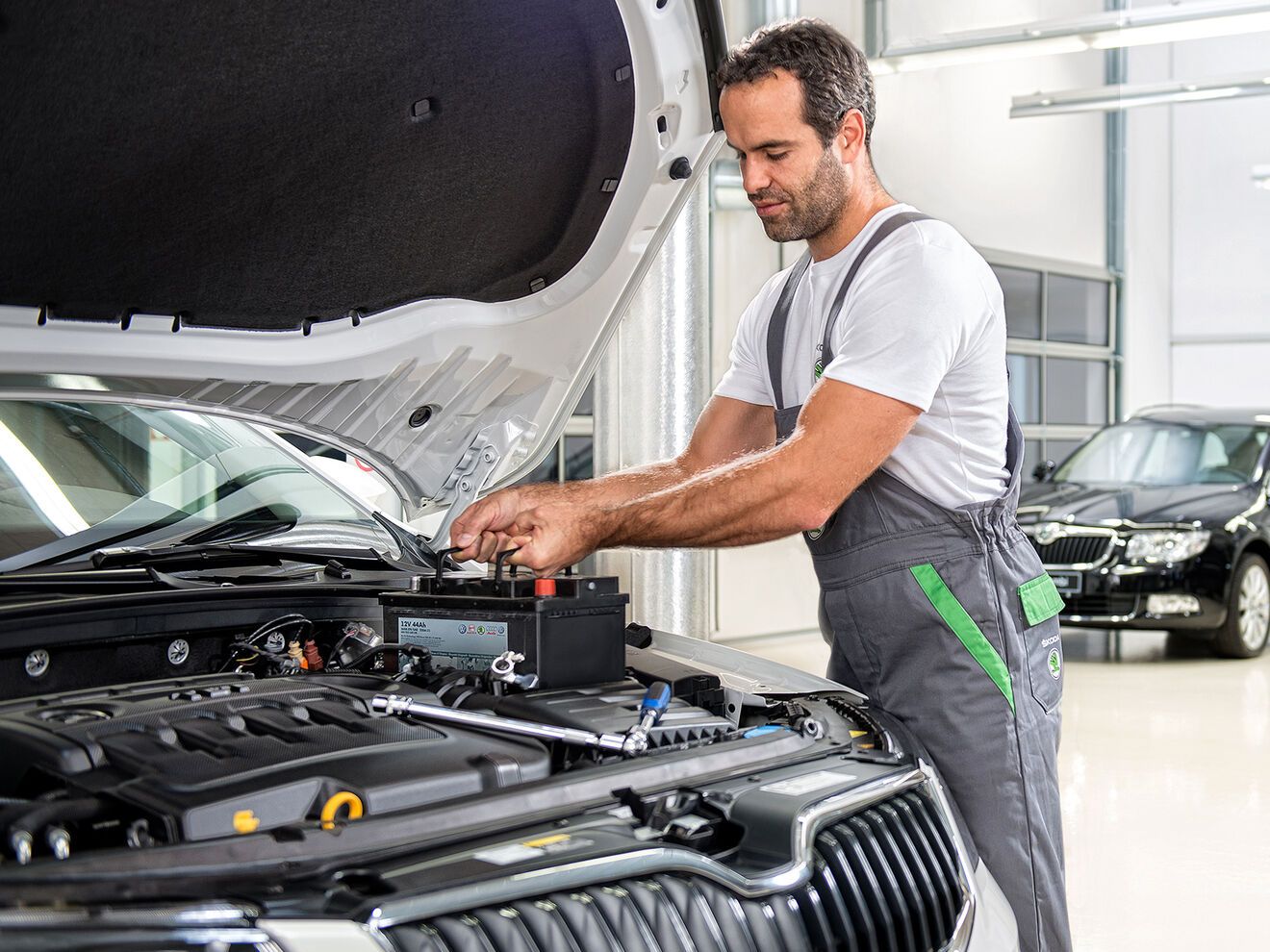 Ein Škoda Mechaniker wechselt die Autobatterie bei einem Škoda