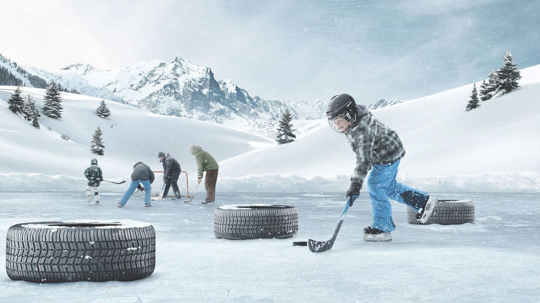 Škoda Winterreifen liegen auf einer Eisfläche. Kinder spielen Eishockey.