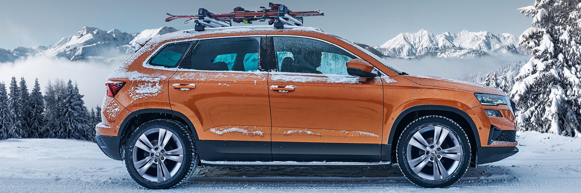 Ein Škoda Karoq mit Skiträger parkt in winterlicher Landschaft