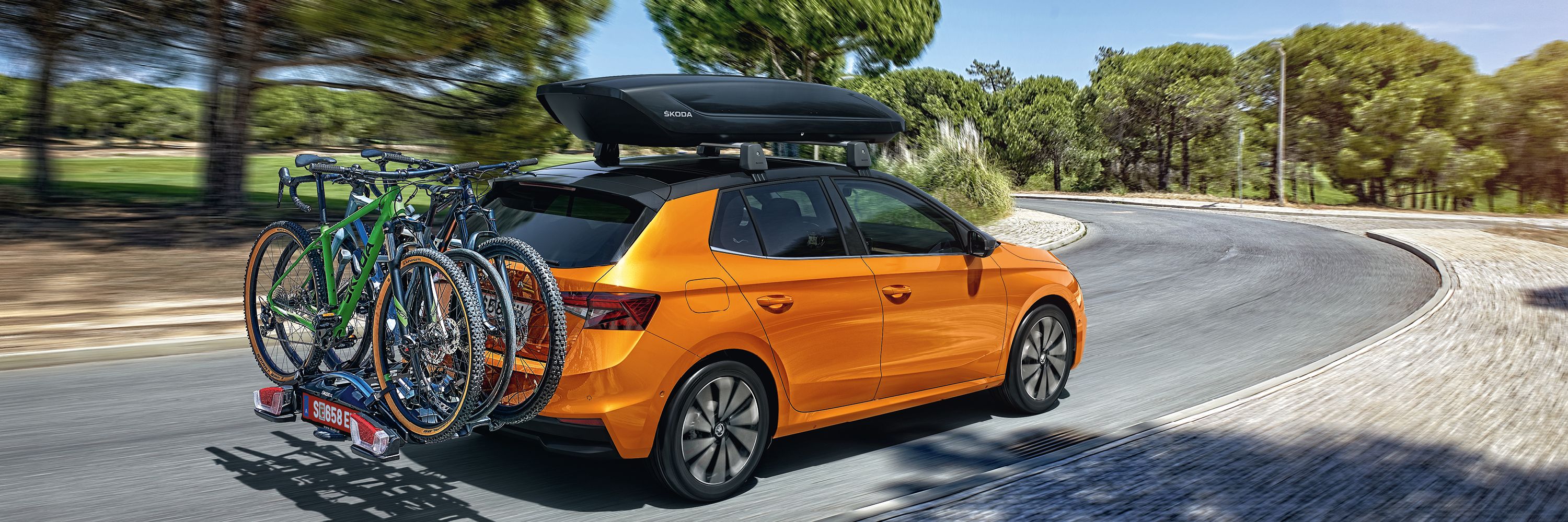 Škoda Fabia in orange mit Dachbox und Fahrrad-Heckträger