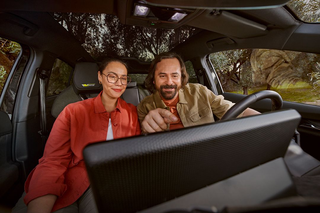 Ein Mann und eine Frau informieren sich am Infotainmentsystem im Cockpit eines Škoda