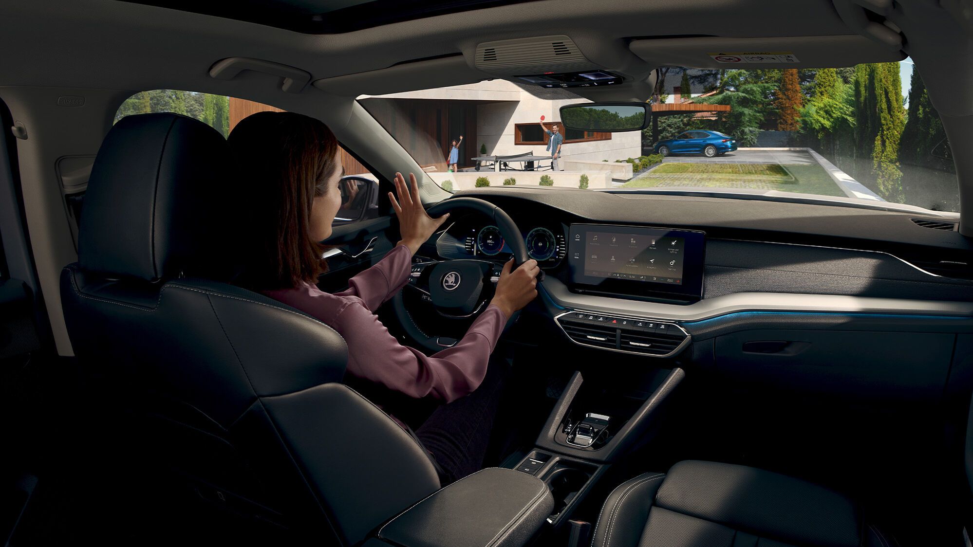 Mulher ao volante de um Škoda  Octavia Break Ambition na perspetiva de um passageiro dos bancos traseiros 