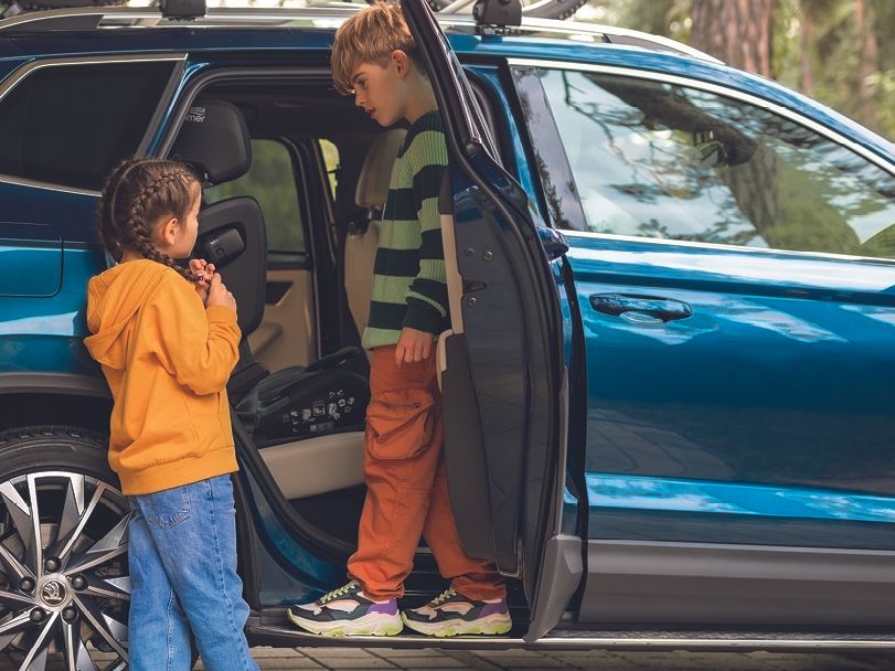 Zwei Kinder beim Einsteigen in einen blauen Škoda Karoq