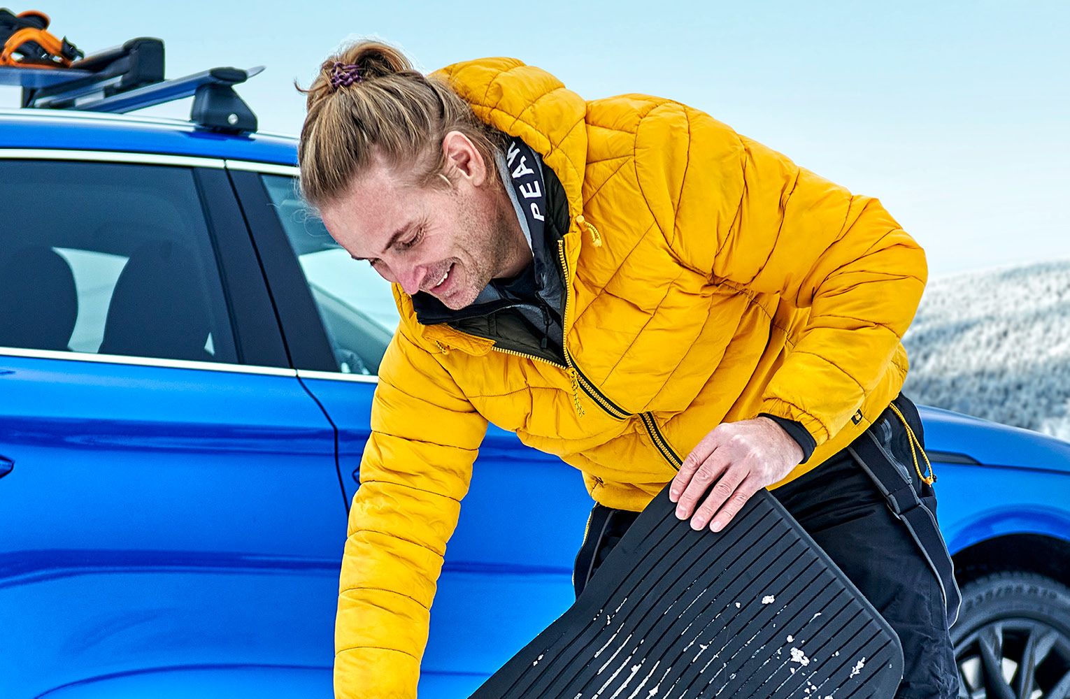 Ein Mann kehrt Schnee von einer Škoda Fußmatte