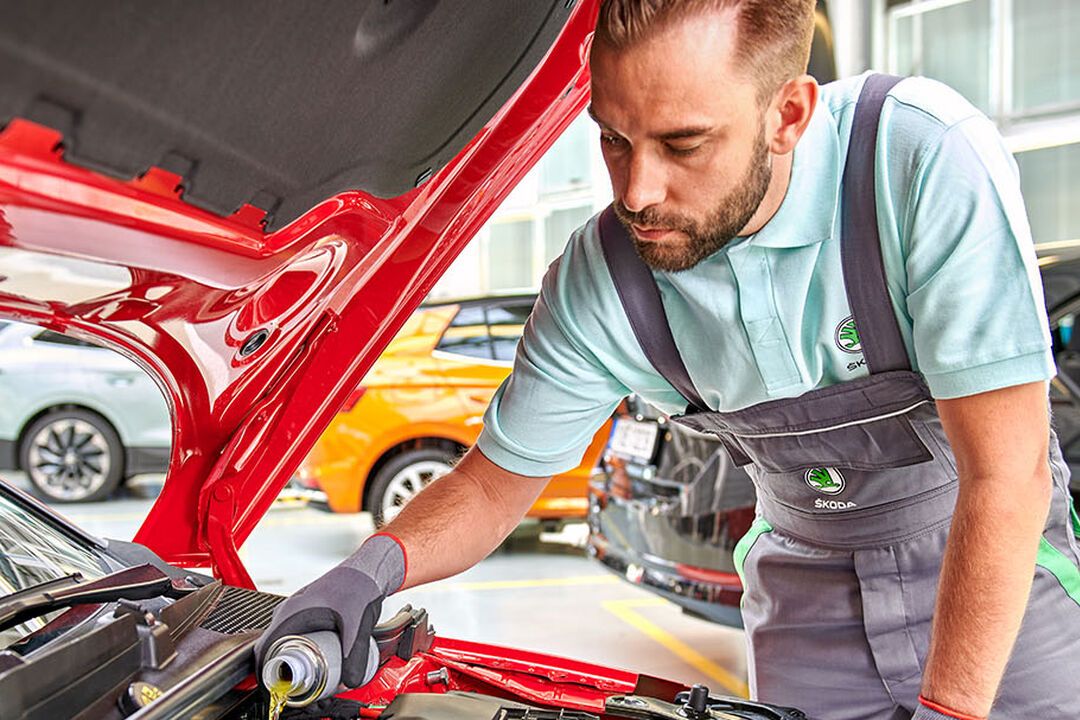 Ein Škoda Techniker beim Nachfüllen von Öl