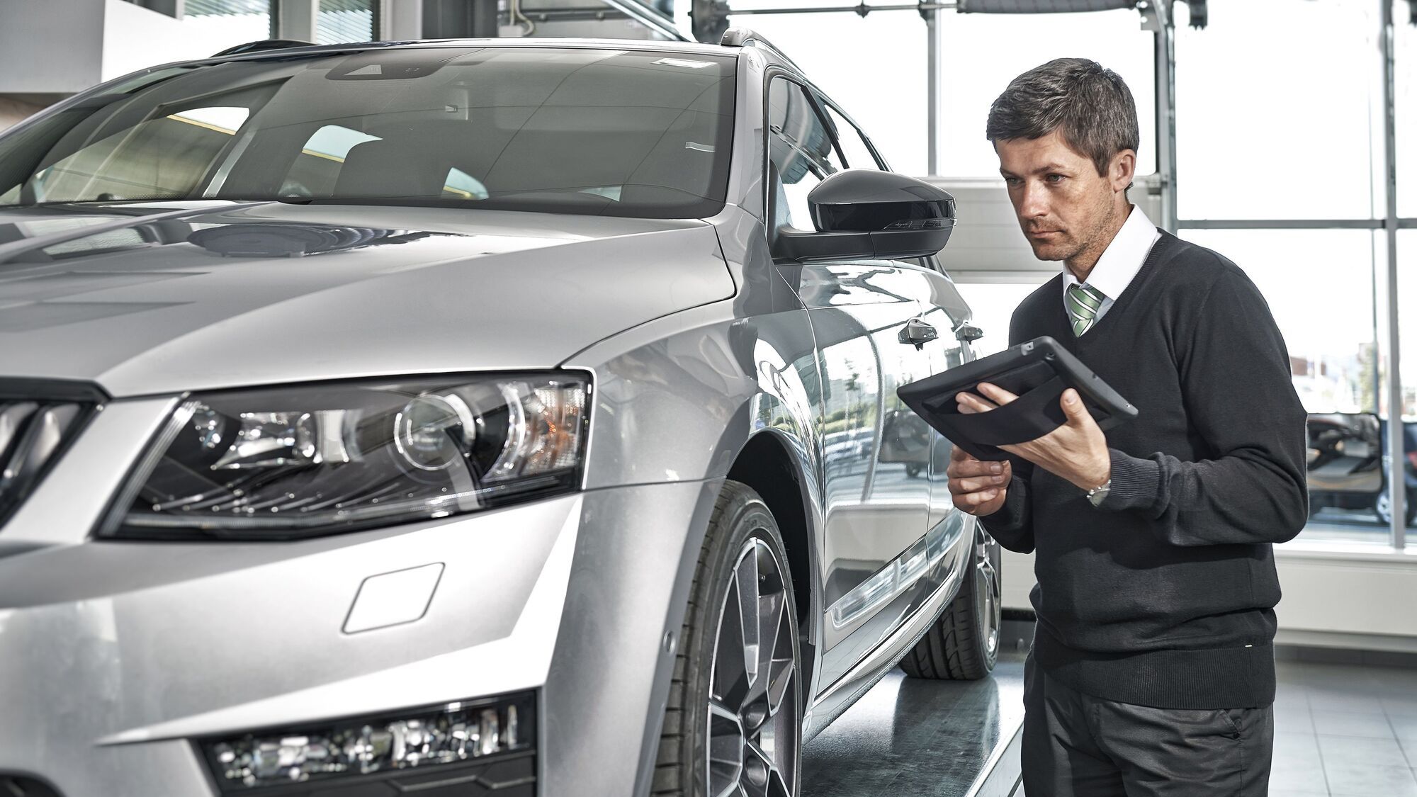 A technician doing check on a silver Škoda in the service center