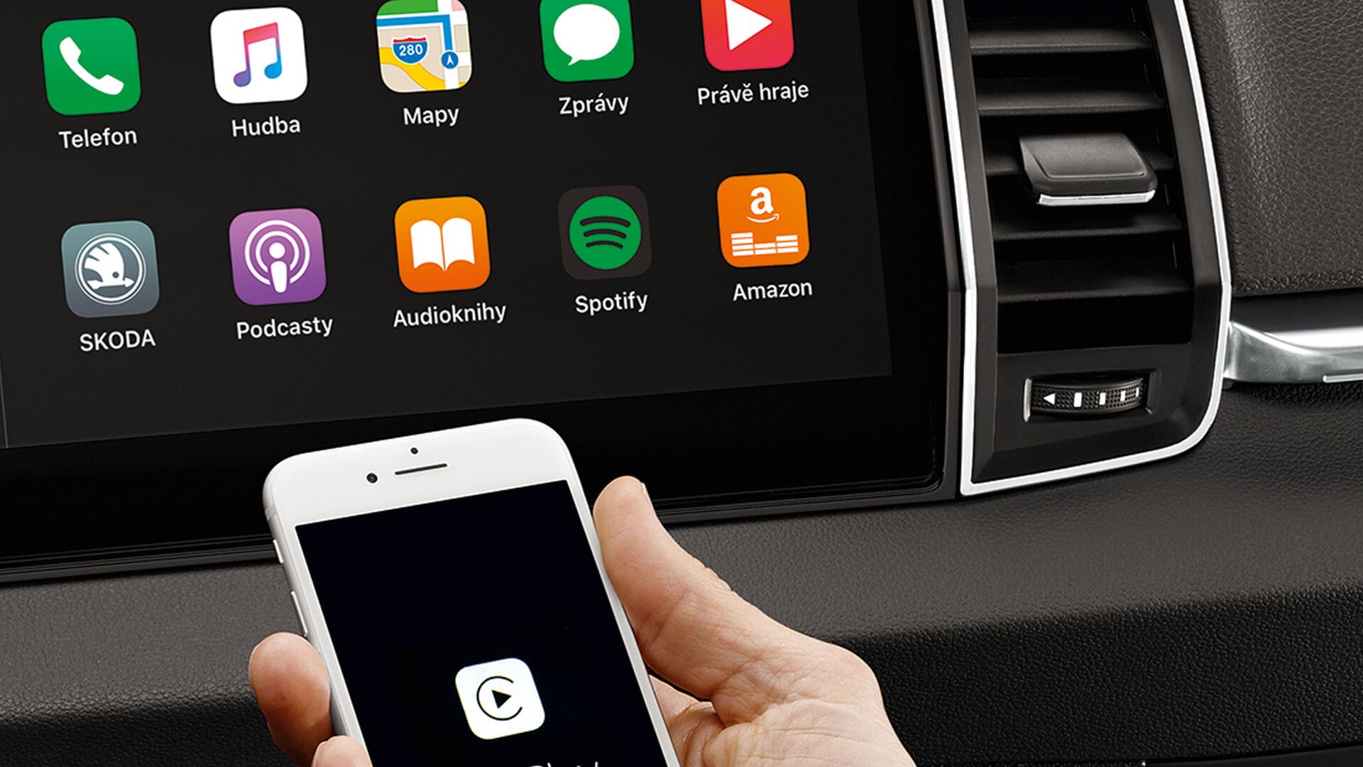 Një smartfon i lidhur me CarPlay mbahet përpara ekranit të një automjeti Škoda