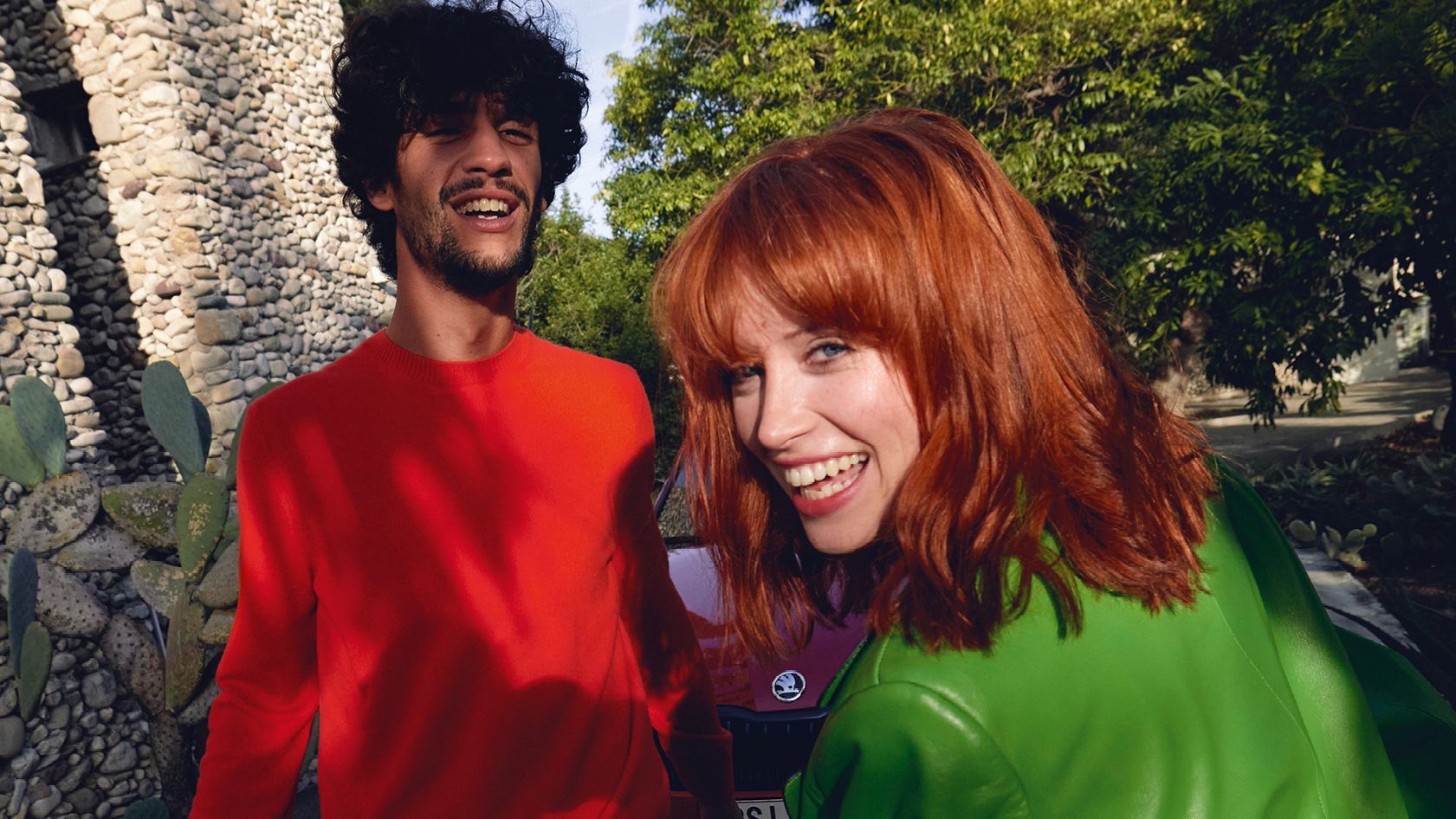 Ein Mann und eine Frau im Urlaub, im Hintergrund ein roter Škoda