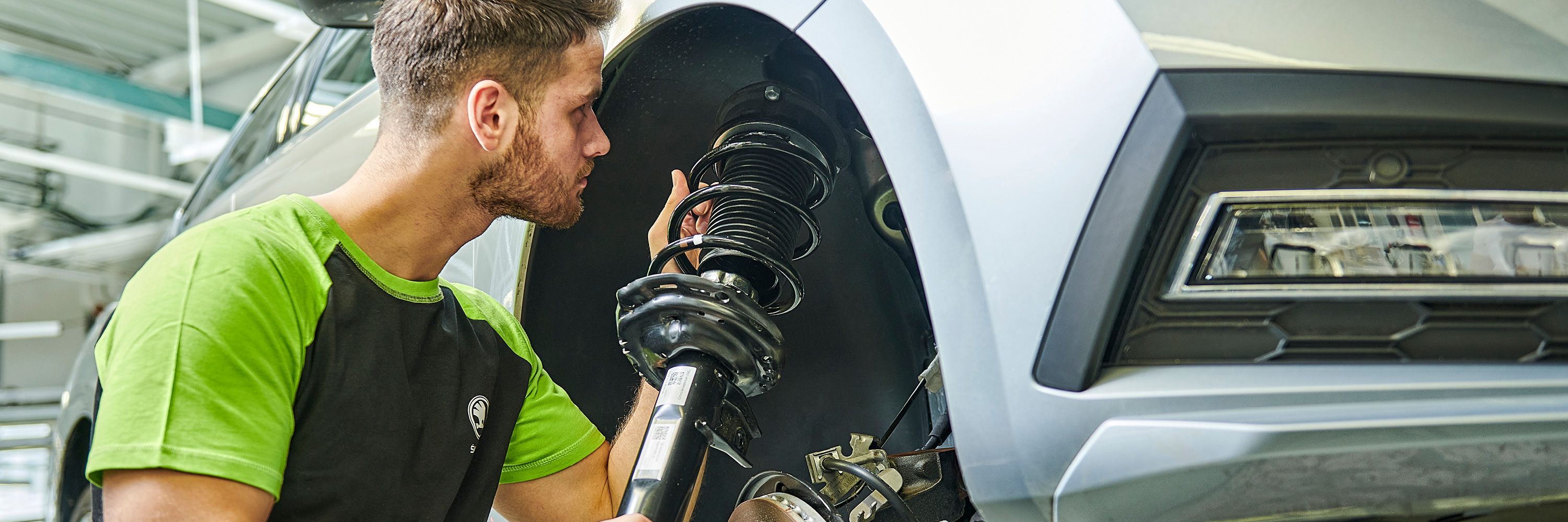 Ein Škoda Mechaniker wechselt die Stoßdämpfer bei einem Škoda