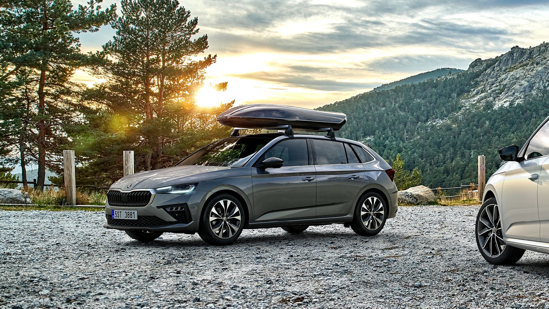 Ein Škoda Scala und ein Škoda Kamiq mit Dachbox parken in einer herbstlichen Berglandschaft.